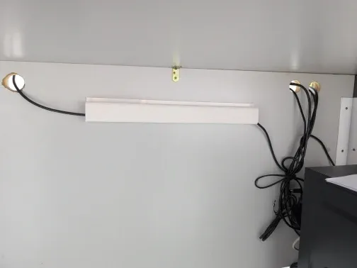 Weißer Kabelkanal, vom Käufer unter einer weißen Platte montiert, mit geführten Kabeln